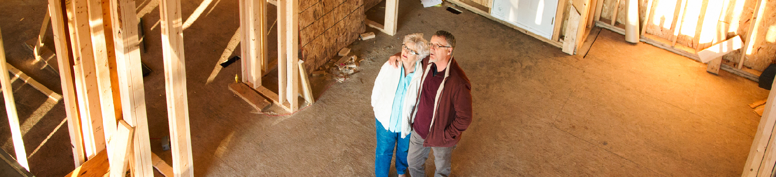 Senior couple standing in the construction zone of their dream home.